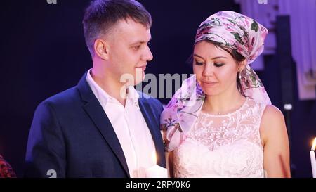 wedding traditions, ceremonies. the newlyweds are holding a white large candle-symbol of the family hearth, happiness and well-being. parents light a candle of the newlyweds with their candles. High quality photo Stock Photo