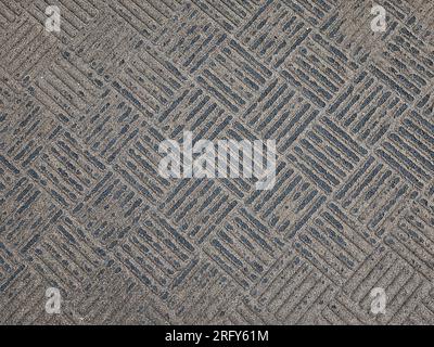Worn rubber tread floor mat with brown and black square tile pattern Stock Photo