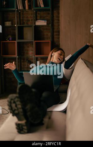 Excited girl waving her hands up and feeling relieved after she finished her online exam successfully at the coffee shop Stock Photo