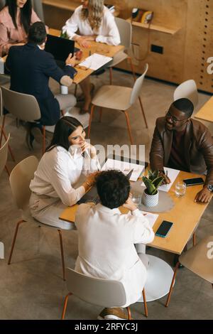 Young, multiracial coworkers having fun conversation and smiling while working together. Above view shot Stock Photo