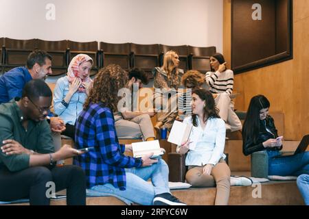 Diverse group of creative people having fun at work while taking a break from work. Multiracial business colleagues working together at small amphithe Stock Photo