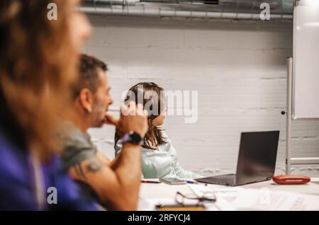 Age diverse team of amateur businesspeople looking at the whiteboard and learning at the office Stock Photo