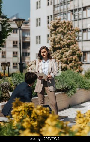 Male and female executives discussing project during meeting out in the city, on a beautiful sunny day Stock Photo