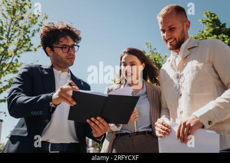 Beautiful stylish young investors discussing business projects, working in a good atmosphere outdoors. Working remotely Stock Photo