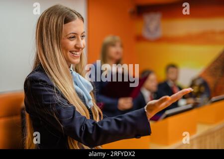 Young and beautiful teacher gesturing to the students in the conference room Stock Photo
