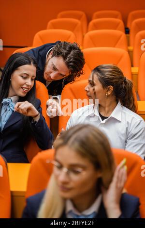 Three students talking and not paying attention in class Stock Photo