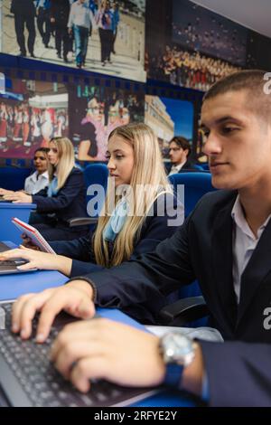 Young and well-dressed students working on their laptops in class Stock Photo