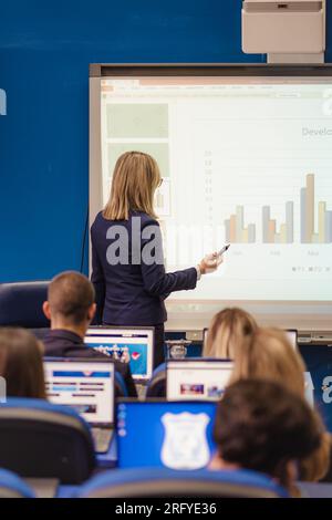 Professor presenting and giving a lecture about graphs to her students in a classroom Stock Photo
