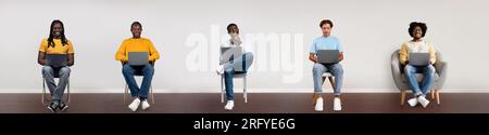 Collage with multiracial male freelancers using laptops, sitting on chairs over light background, collage, panorama Stock Photo