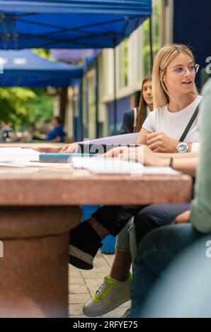 Group of young classmates sitting and talking outside Stock Photo