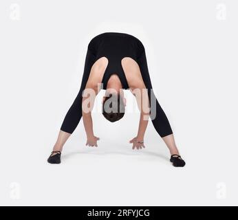 Specialized trauma releasing exercises for elderly people, 55 years old woman trainer posing for exercises. Hamstring pose, in the studio isolated on Stock Photo