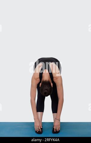 Specialized trauma releasing exercises for elderly people, 55 years old woman trainer posing for exercises. Hamstring pose, in the studio isolated on Stock Photo