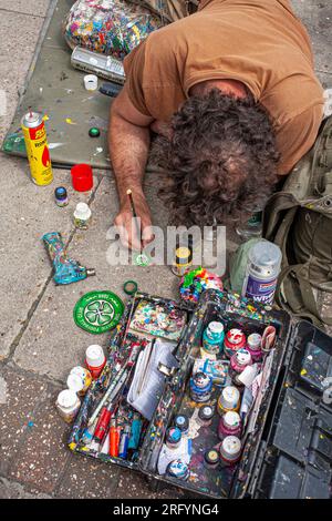 Artist Ben Wilson, who creates tiny paintings on chewing gum on the pavement, discusses his work with onlookers, North London, UK Stock Photo