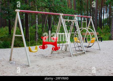 Colorful playground in park with swings, no kids. Vacation with children in city park. Stock Photo