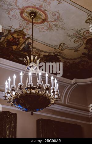 Royal crystal historical chandelier with candles. Baroque architecture and details. Dark beauty aesthetics. Vertical shot Stock Photo