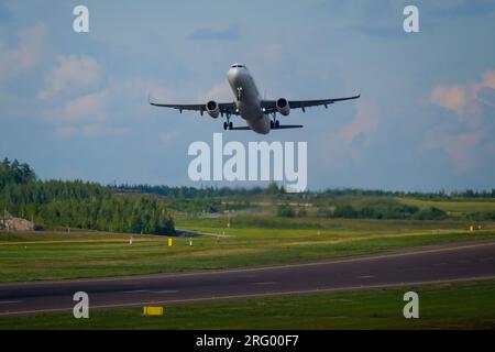 Helsinki / Finland - AUGUST 5, 2023: An airplane taking off from the runway against a bright cloudy sky. Stock Photo