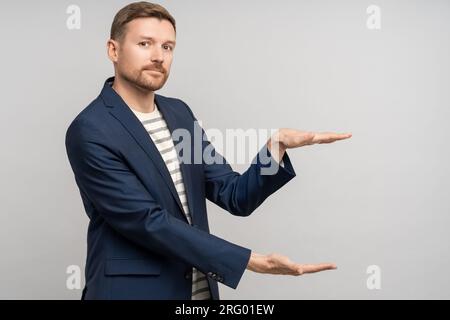 Interested man promoter in business suit shows with hands size of discount for sale on studio wall Stock Photo