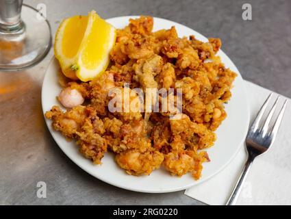 Battered fried baby squid with lemon Stock Photo