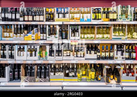 Italy - August 05, 2023: Bottles of wine of various types and brands in cardboard boxes on shelves for sale at low prices in Italian discount store Stock Photo