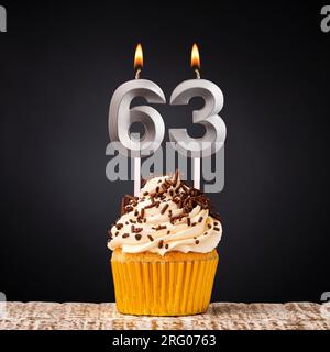 Birthday candle number 63 - Anniversary cupcake on black background Stock Photo