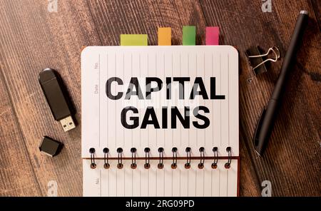 Business concept. On the financial charts lies a pen and a sign with the inscription - capital gain. Stock Photo