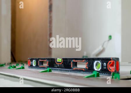 Tile levelling system, four plastic green clips with wedges. Close-up view, selective focus, blurred background. Stock Photo