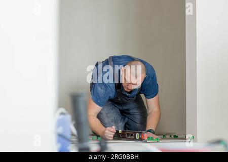 A male construction worker installs a large ceramic tile. Stock Photo