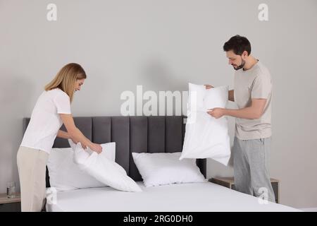 Couple changing bed linens in room. Domestic chores Stock Photo