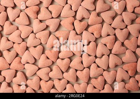 Many heart shaped vitamins for pets on beige background, flat lay Stock Photo