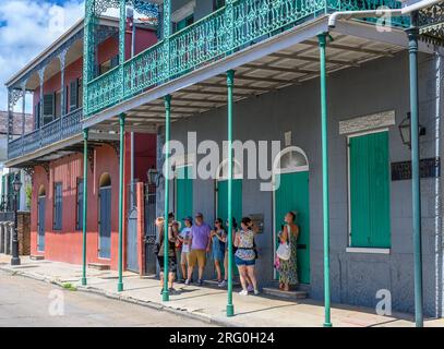 NEW ORLEANS, LA, USA - AUGUST 6, 2023: Tour group beneath the gallery of the historic Felton Arms building on Chartres Street in the French Quarter Stock Photo