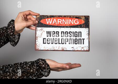 Web Design Development Concept. Warning sign with text in woman hands. Stock Photo