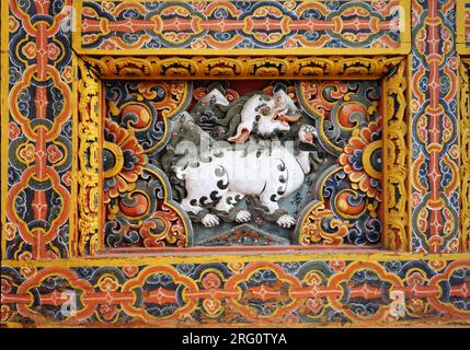 Closeup of a carved painted wooden relief featuring a mythical white snow lion surrounded by intricate painted embellishments at Punakha Dzong, Bhutan Stock Photo