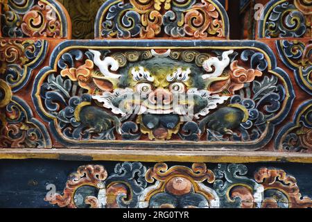 Detail of fierce carved and painted wooden dragon face cartouche at Punakha Dzong in the Kingdom of Bhutan. The dragon, or druk, is Bhutan's protector Stock Photo