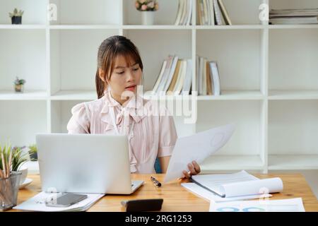 employee with paper work inside office, female financier worker thinks about contracts and reports with charts and graphs, successful woman uses Stock Photo