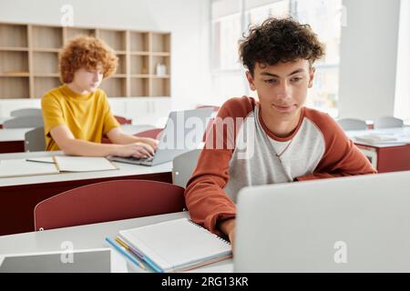 back to school, teen students using laptops in classroom, e-study, education, classmates and gadgets Stock Photo