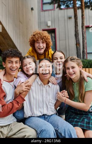 cultural diversity, back to school happy african american teacher hugging with positive teenage kids Stock Photo