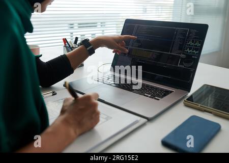 Muslim software developer pointing at laptop screen with programming code Stock Photo