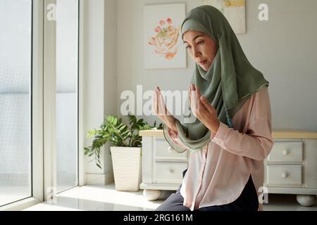 Serious concentrated muslim woman praying at home Stock Photo