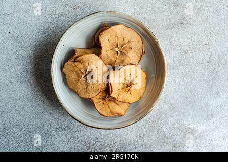 Top view of slices of dried apples served in ceramic bowl against blurred gray background Stock Photo