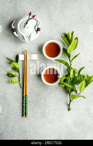 Top view of tea set in Asian style with lemon leaves and chopsticks against gray background Stock Photo