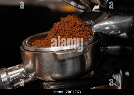Fresh ground coffee in portafilter of professional grinder in cafe Stock Photo