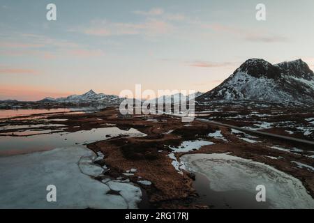 Amazing view of snowy mountains and frozen river with snow in winter day under cloudy sky located at Lapland Stock Photo