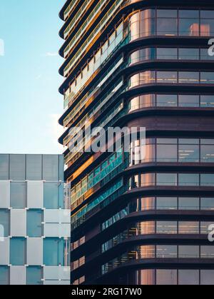 Contemporary skyscrapers with glass mirrored windows against blue cloudy sky on street Stock Photo