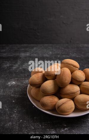 photo of peanuts with boiled condensed milk on a plate, on a dark background Stock Photo