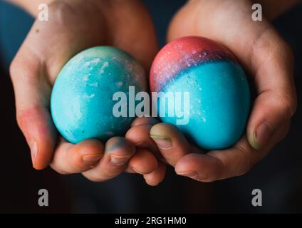 Close up of child's hands holding two colored Easter eggs. Stock Photo