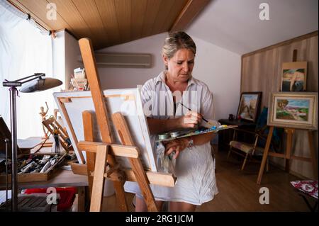 Front view of a senior woman painting a picture. Stock Photo