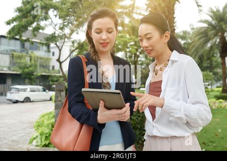 Diverse business colleagues discussing document on tablet computer when standing outdoors Stock Photo