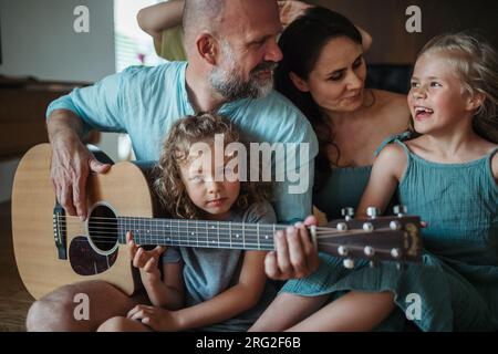 Father playing on guitar for his family. Stock Photo