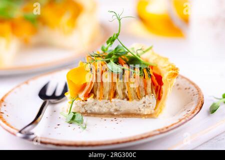 Homemade vegetable tart with carrot, zucchini and pumpkin on white wooden table. Spiral vegetable tart. Stock Photo
