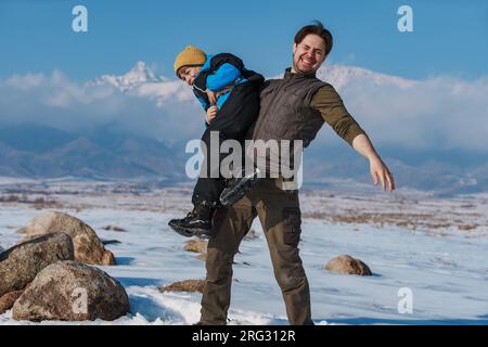 Happy father and child having fun on mountains background at winter season Stock Photo